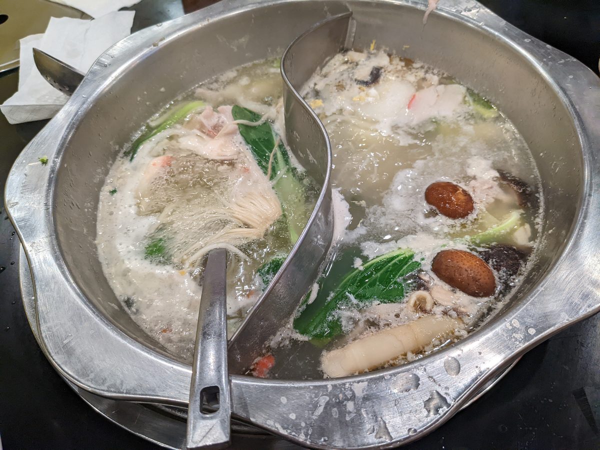 A bubbling Sichuan hotpot with a red broth at the table