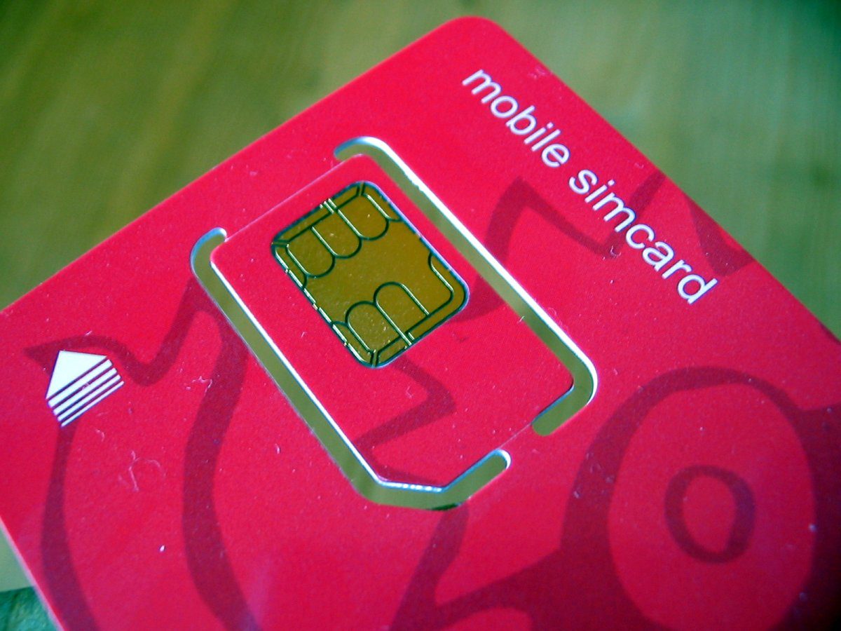 A SIM card beside a phone, contrasting physical and digital options
