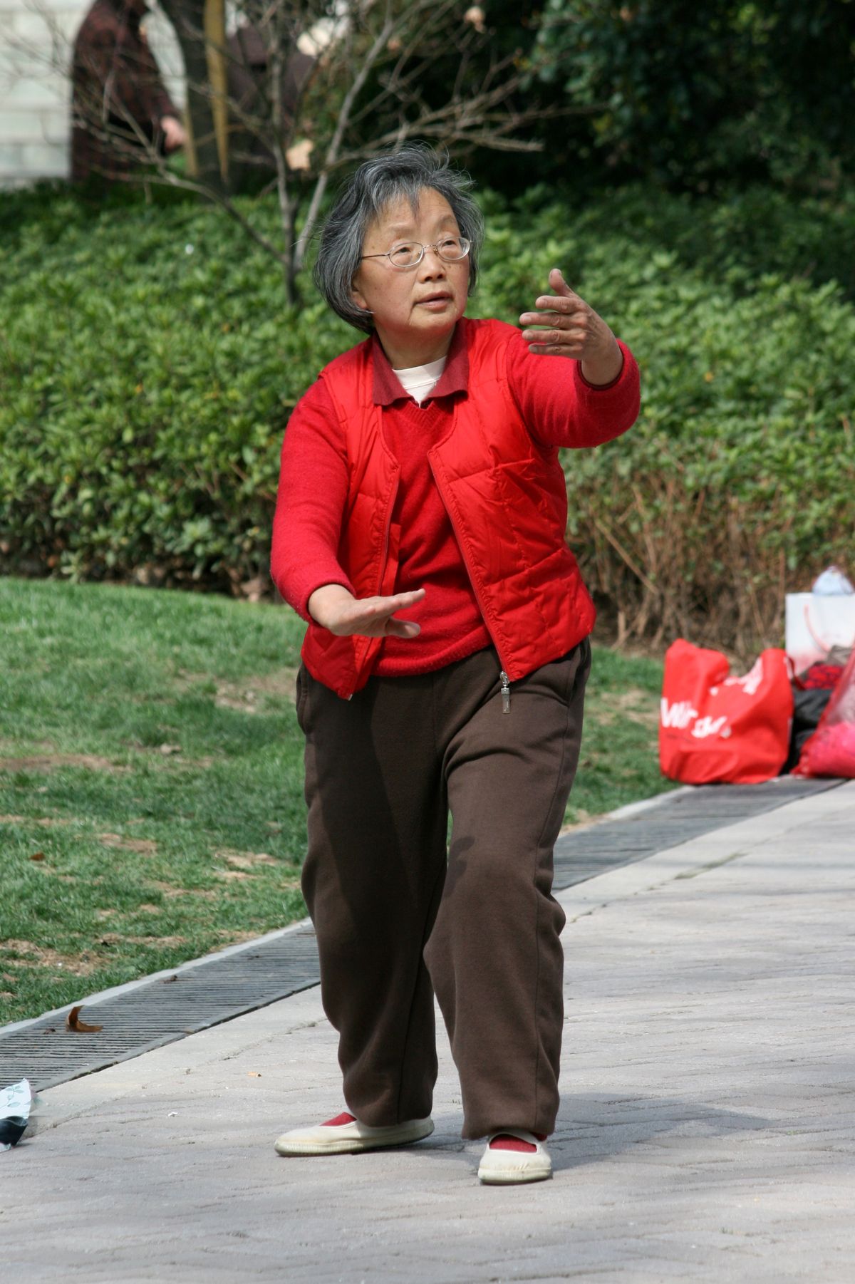 An elderly woman practicing tai chi in a park