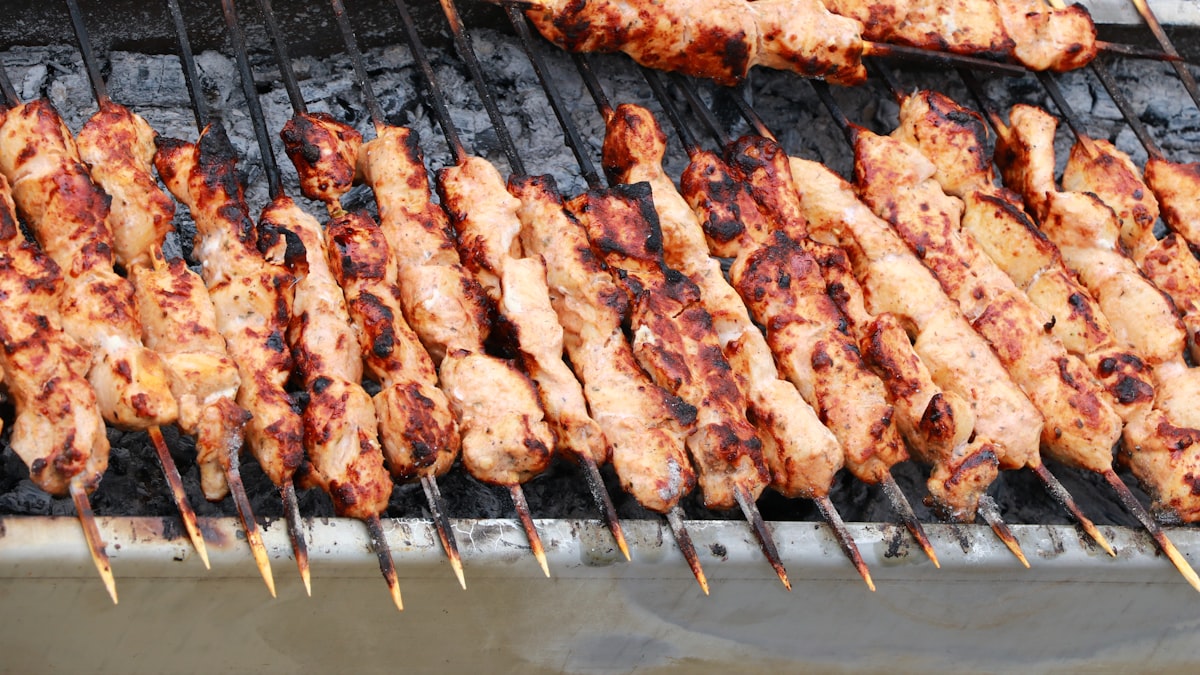 Cumin-dusted lamb skewers grilling over charcoal