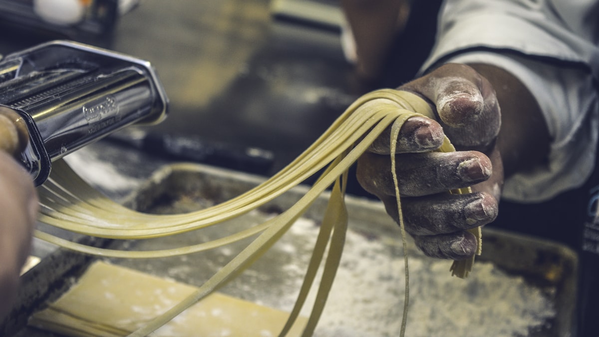 A chef stretching hand-pulled noodles from a lump of dough